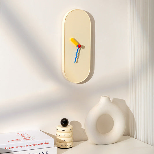 Cream oval wall clock with wavy blue and yellow hands and red ball center